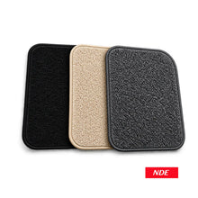 Three rectangular textured floor mats or pads shown overlapping on a white background, in black, beige, and dark gray/black. A small red NDE logo appears in the bottom right corner.