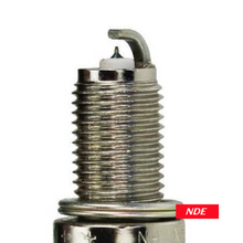A close-up of a metallic spark plug with a threaded body and a small red label reading NDE near the base, shown on a plain white background.