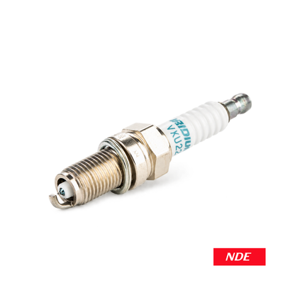 A single spark plug with a white ceramic body, silver metal electrodes, and blue printed text, shown on a plain white background with a small red 'NDE' label in the bottom right corner.